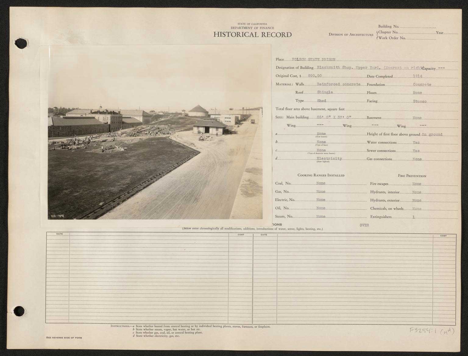 A historical ledger from the California Department of Finance documenting details about the blacksmith shop in the upper yard at Folsom State Prison. The black-and-white photograph shows a wide view of the prison yard with various buildings in the background. The structure designated as the blacksmith shop is visible to the right, completed in 1914 at a cost of $890. The building features reinforced concrete walls, a shingle roof, and concrete foundations. The ledger notes the building's dimensions (25 ft x 37 ft) and various utility connections, such as water and electricity, though it lacks gas connections. The image also shows prisoners working in the yard.